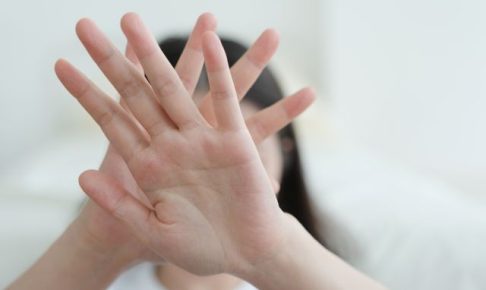 手を顔の前にあてる女性