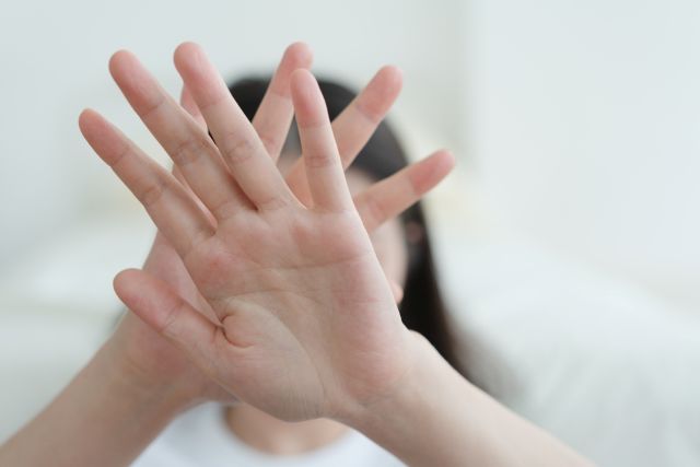 手を顔の前にあてる女性